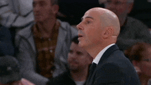 a bald man in a suit and tie is clapping