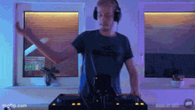 a man wearing headphones and a hollister shirt is playing music on a turntable