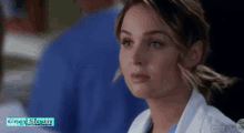 a close up of a woman wearing a white lab coat and a blue scrub .