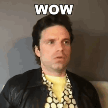a man wearing a polka dot shirt and a leather jacket is making a surprised face with the word wow written above him .