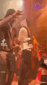 a man in a hoodie is holding a microphone while another man stands behind him .