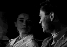 a black and white photo of a man and a woman hugging each other .