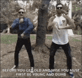 two men are standing next to each other in a park .