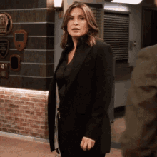a woman in a black suit is standing in a hallway