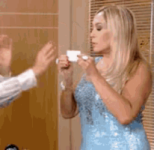 a woman in a blue dress is holding a cup in her hand