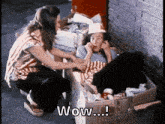 a woman is kneeling down next to a boy in a cardboard box with the words wow written on it .