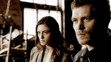 a man and a woman are standing next to each other and looking at each other .