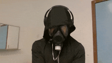 a person wearing a gas mask and headphones looks at the camera