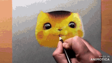 a person is drawing a cat with a pencil on a piece of paper that says made in animatica