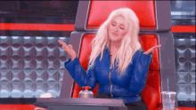 a woman is sitting in a red chair with her arms outstretched .