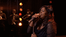a woman singing into a microphone on stage