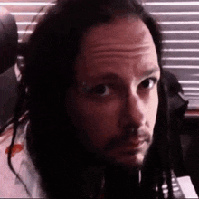 a close up of a man with dreadlocks and a beard looking at the camera .