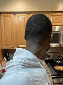 a man in a white shirt stands in a kitchen