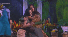 a group of women are hugging each other on a stage in front of a green background .