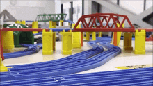 a toy train track with a red bridge and yellow pillars