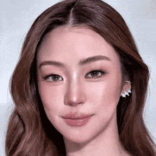 a close up of a woman 's face with long hair and earrings .