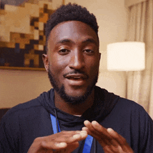 a man wearing a black hoodie and a blue lanyard looks at the camera