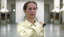 a woman in a white shirt holds a knife in a hallway