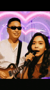 a man playing guitar and a woman singing into a microphone