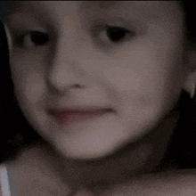 a close up of a child 's face with a slight smile on her face