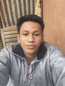 a young man taking a selfie wearing a grey jacket with the letter r on his shirt