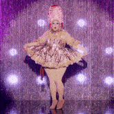 a drag queen wearing a pink wig and a gold dress is dancing on a stage