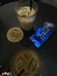 a coaster that says you are enough sits on a table next to two cups of coffee