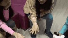 a group of girls are sitting on the floor playing a game with their hands .