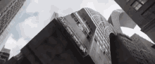 looking up at a tall building in a city surrounded by other tall buildings .