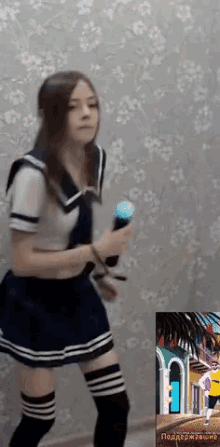 a girl in a sailor outfit is holding a microphone and dancing