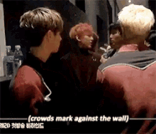 a group of young men are standing next to each other in a room with the words crowds mark against the wall .