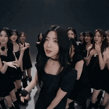 a group of young women in black dresses are dancing together