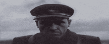 a black and white photo of a man wearing a military hat