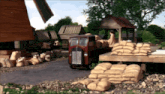 a red truck is parked in front of a wooden windmill