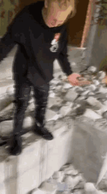 a man in a black shirt is standing on a pile of papers .