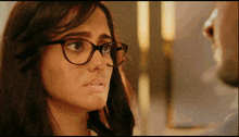 a woman wearing glasses looks at the camera with a serious look on her face