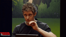 a man is sitting in front of a screen that says dungeons & dragons adventures