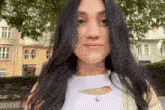 a woman with long black hair is wearing a white shirt and a necklace with a heart pendant .