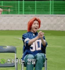 a person with red hair is sitting in a chair with their hands in the air .