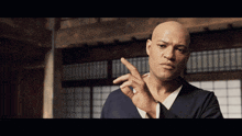 a bald man in a blue shirt is pointing his finger