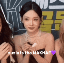 a woman in a black dress with the words zuzia is the maknae written above her