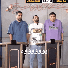 three men standing next to each other with one wearing a purple question mark t-shirt