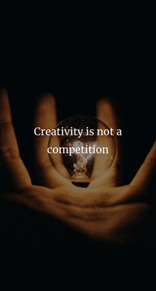 a hand is holding a light bulb with the words creativity is not a competition