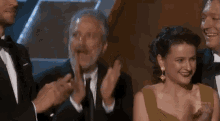 a group of people in tuxedos are clapping their hands at an awards show .