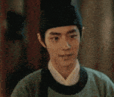 a young man wearing a green shirt and a black hat .