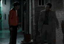 two men standing next to each other in a dark room