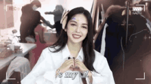 a woman in a white shirt is making a heart with her hands and says it 's my