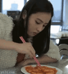 a girl is eating a plate of food with chopsticks and the website yh31.com is in the corner