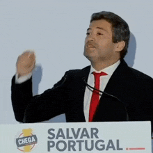 a man stands at a podium with a sign that says salvar portugal on it