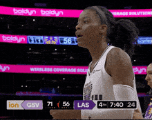 a female basketball player stands in front of a scoreboard that says las